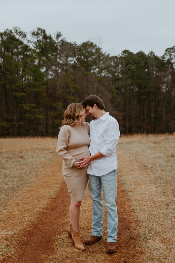 husband and wife embracing during winter maternity session by georgia family photographer kattie jackson